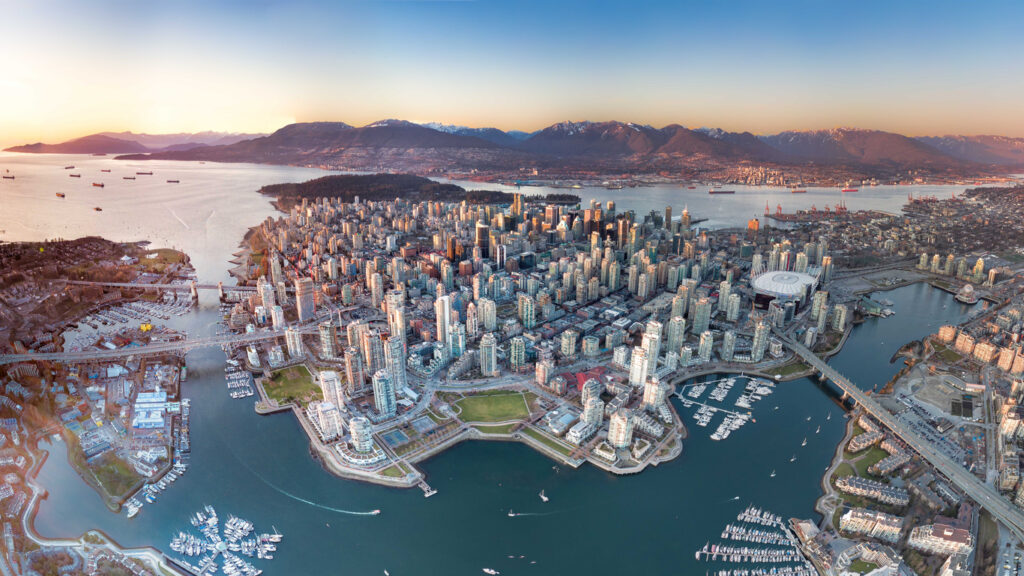 Luftaufnahme von Downtown Vancouver mit Marinas, Brücken und Bergen im Abendlicht.