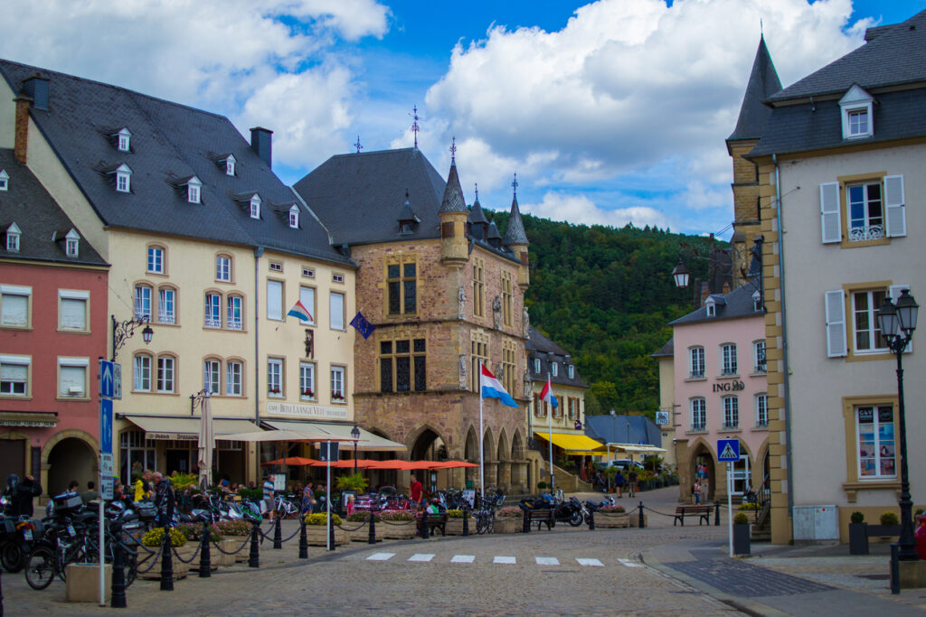 Historische Häuser und altes Rathaus mit Caféterrassen auf einem Platz.