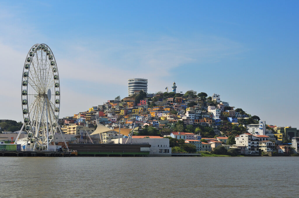 Riesenrad vor bunten Hügelhäusern am Flussufer in Guayaquil.