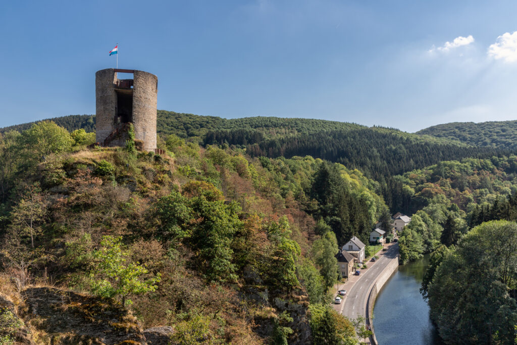 Alter Burgturm auf einem Felsen über dem Fluss, umgeben von Wald nahe Esch-sur-Sûre.