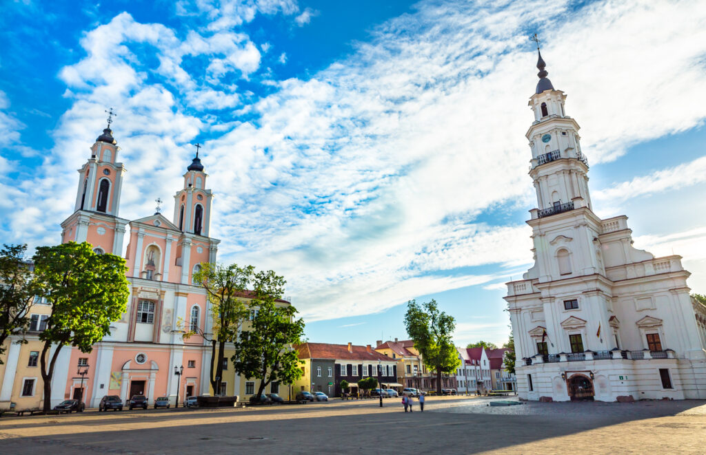 Der weiße Rathausturm von Kaunas steht neben der Jesuitenkirche auf dem weiten Platz.
