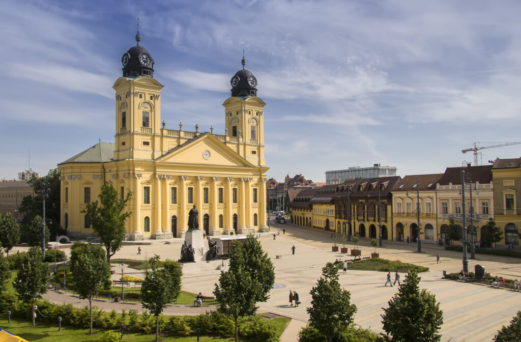 Die Große Reformierte Kirche steht an einem weiten Platz mit Statue und historischen Fassaden.