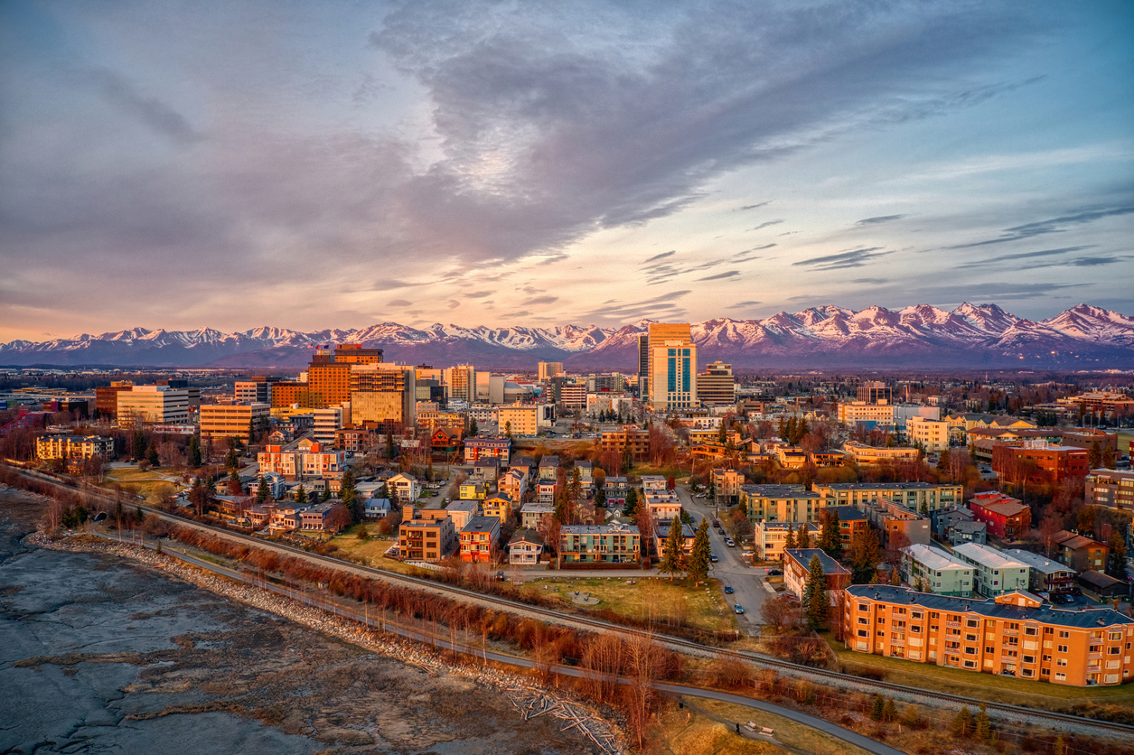 Luftaufnahme der Innenstadt von Anchorage mit schneebedeckten Chugach Mountains im Hintergrund.