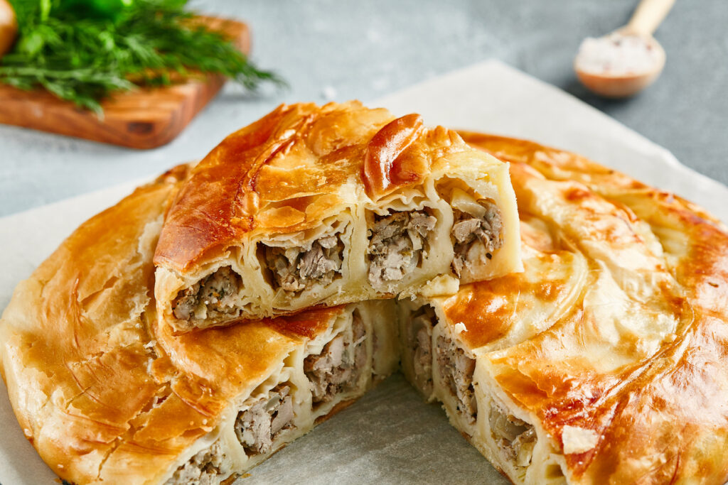 Stücke eines fleischgefüllten Burek, die die gerollten Teigschichten zeigen.