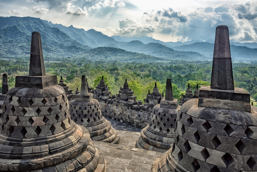 Stein-Stupas des Borobudur mit Blick auf bewaldete Hügel und Berge.