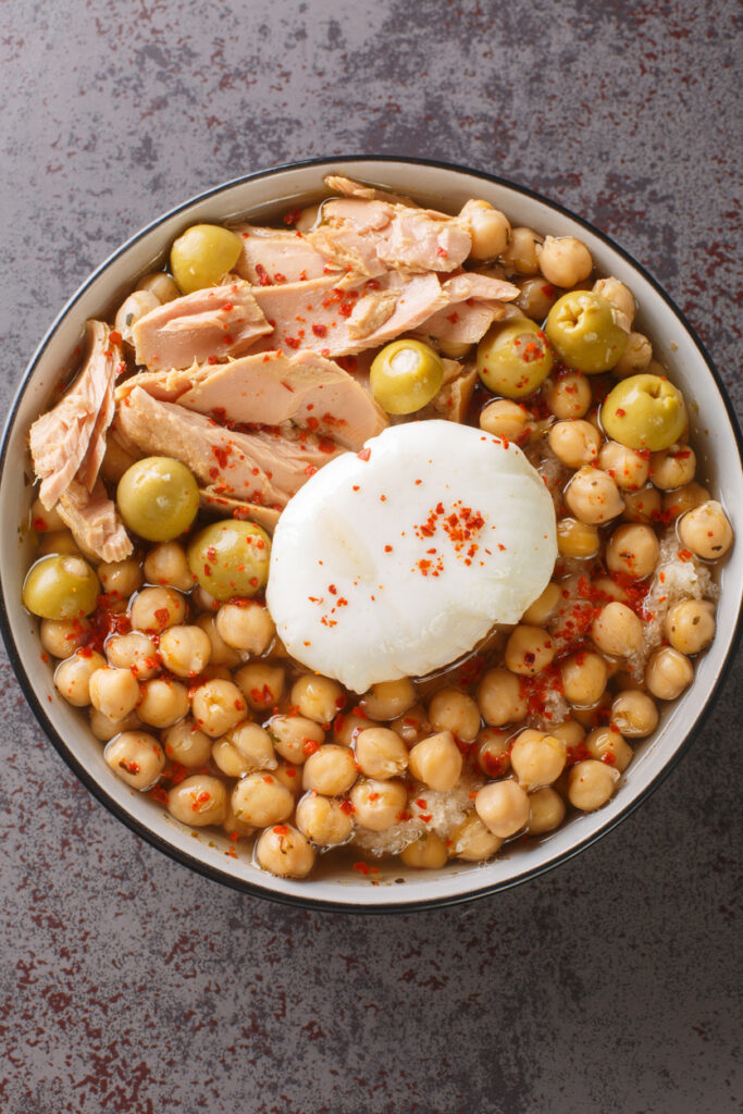 Schüssel mit Lablabi aus Kichererbsen, Thunfisch, grünen Oliven und Ei.