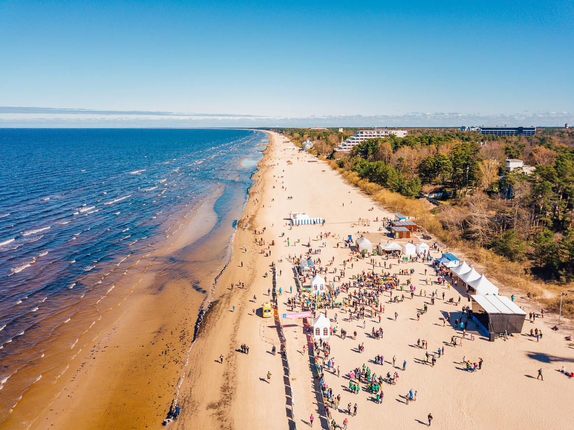 Drohnenaufnahme eines breiten Strandes mit vielen Menschen und Zelten in Jūrmala.