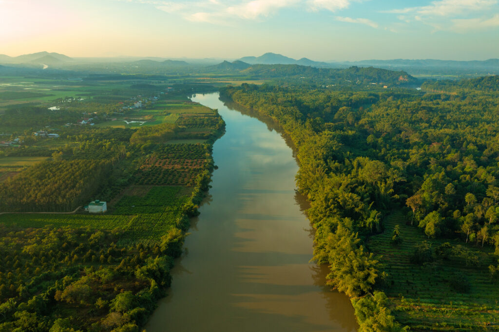 Luftaufnahme von Fluss, Wald und Feldern im warmen Morgenlicht.