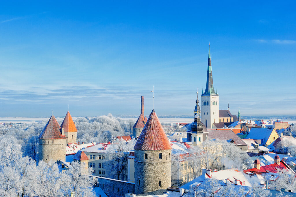 Verschneite Altstadt mit roten Ziegeldächern und der markanten St.-Olai-Kirche.