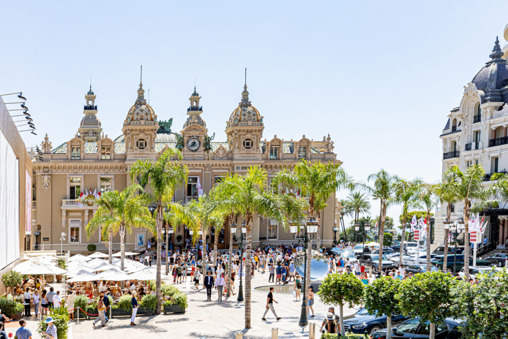Historische Casinofassade mit Palmen, vielen Menschen und sommerlichem Licht.