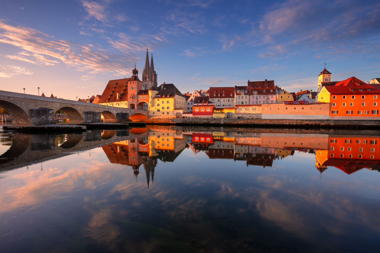 Steinerne Brücke, Altstadt und Domspitzen spiegeln sich golden in der ruhigen Donau.
