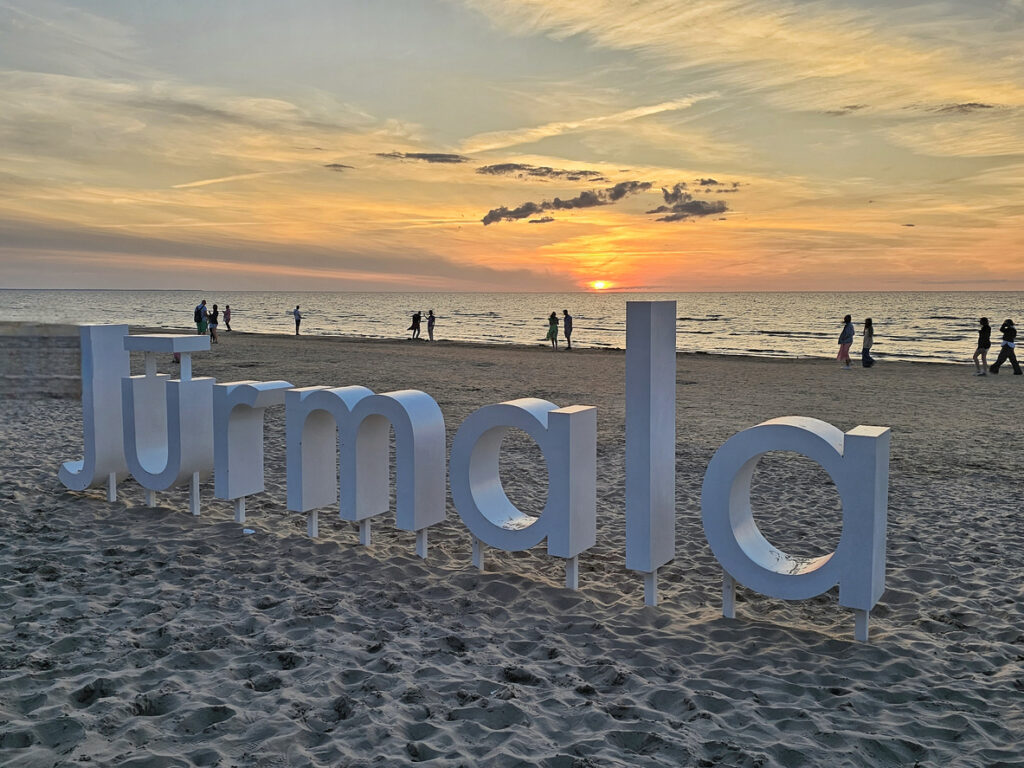 Großer weißer „Jūrmala“ Schriftzug am Abend vor der untergehenden Sonne.