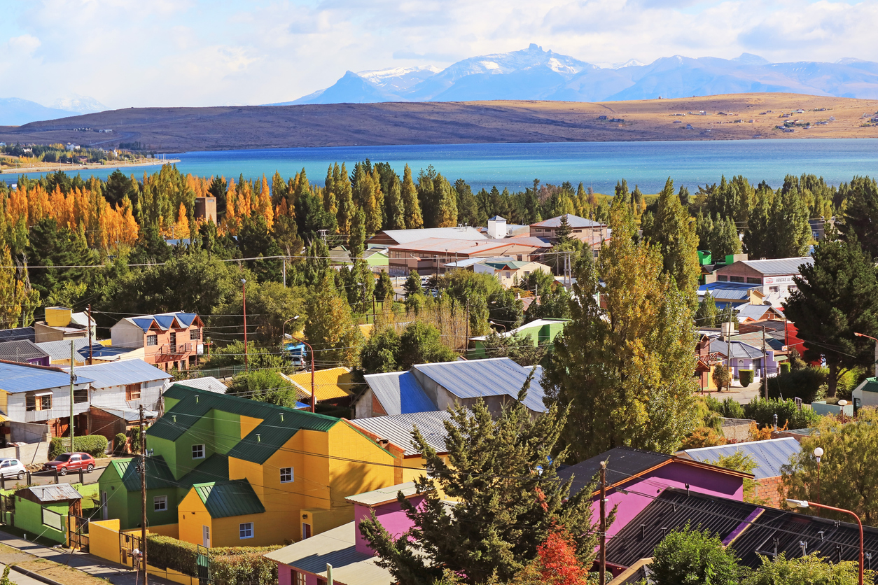 Bunte Häuser von El Calafate mit Blick auf den Lago Argentino und schneebedeckte Berge im Hintergrund.