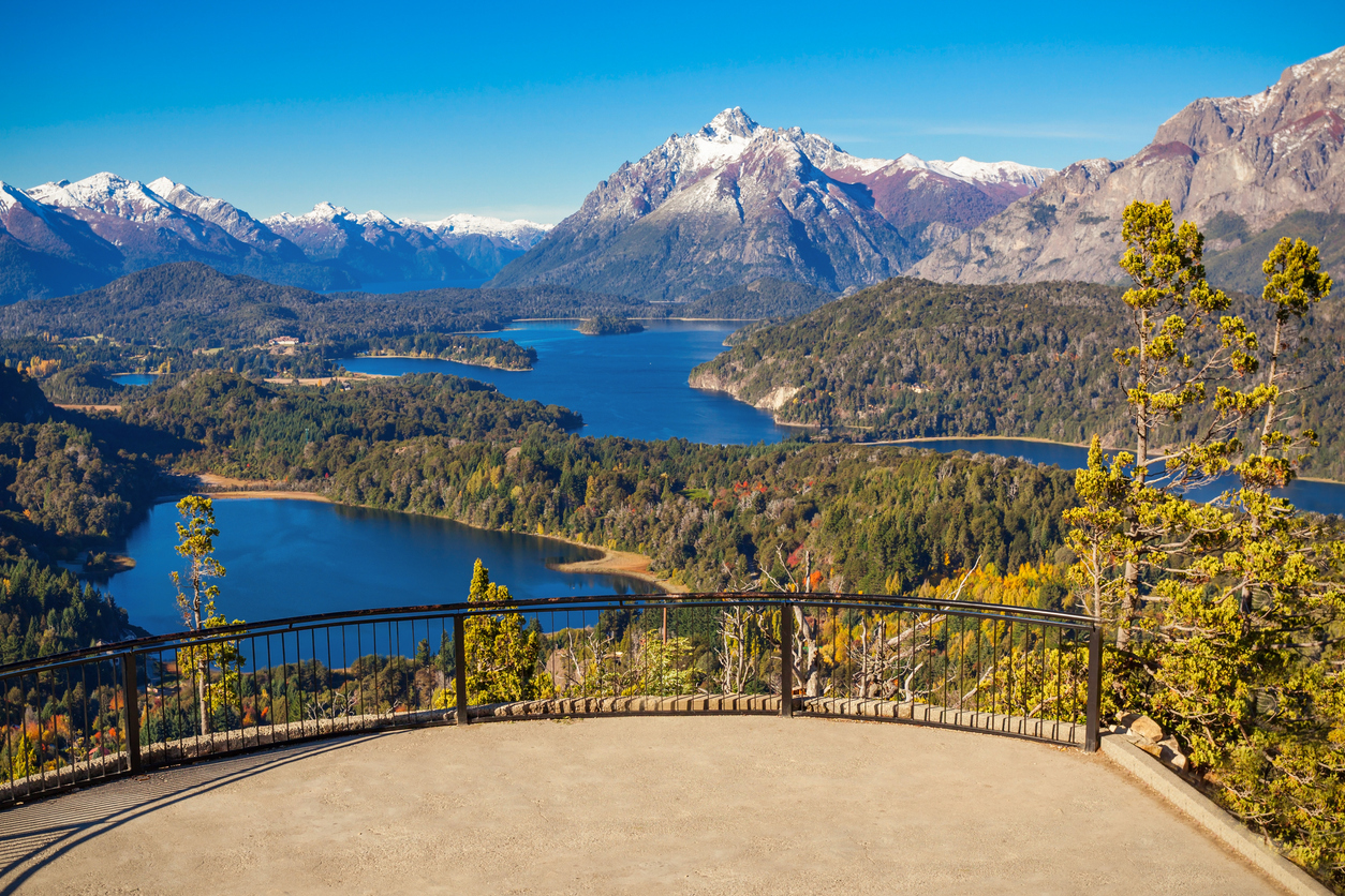 Aussichtsplattform mit Geländer über blauen Seen, Wäldern und schneebedeckten Bergen bei Bariloche.