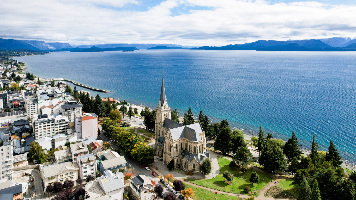 Luftaufnahme der Kathedrale von Bariloche am Ufer des Nahuel-Huapi-Sees mit Stadt und Bergen.