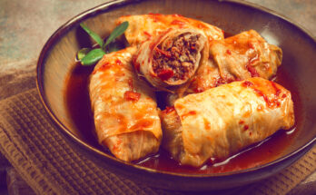 Mehrere Sarma liegen in einer Schüssel mit roter Tomatensauce.