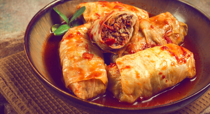 Mehrere Sarma liegen in einer Schüssel mit roter Tomatensauce.