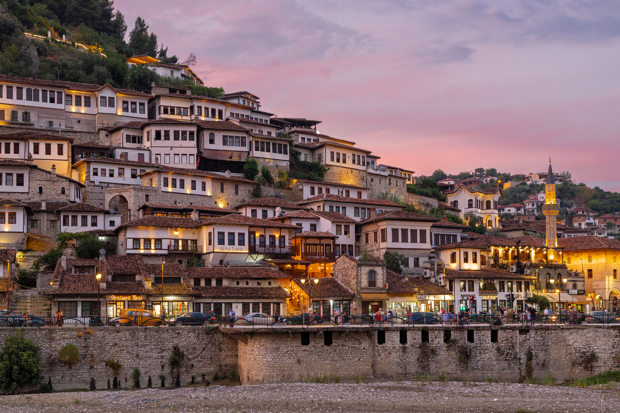 Osmanische Häuser über dem Fluss in Berat vor rosa Abendhimmel.