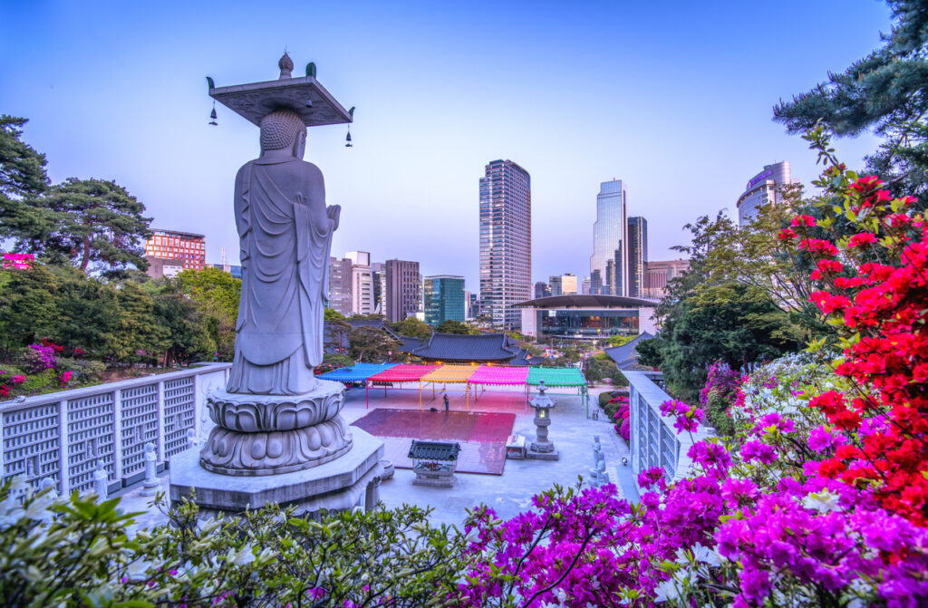 Große Buddha-Statue im Bongeunsa-Tempel vor Seouls moderner Skyline.
