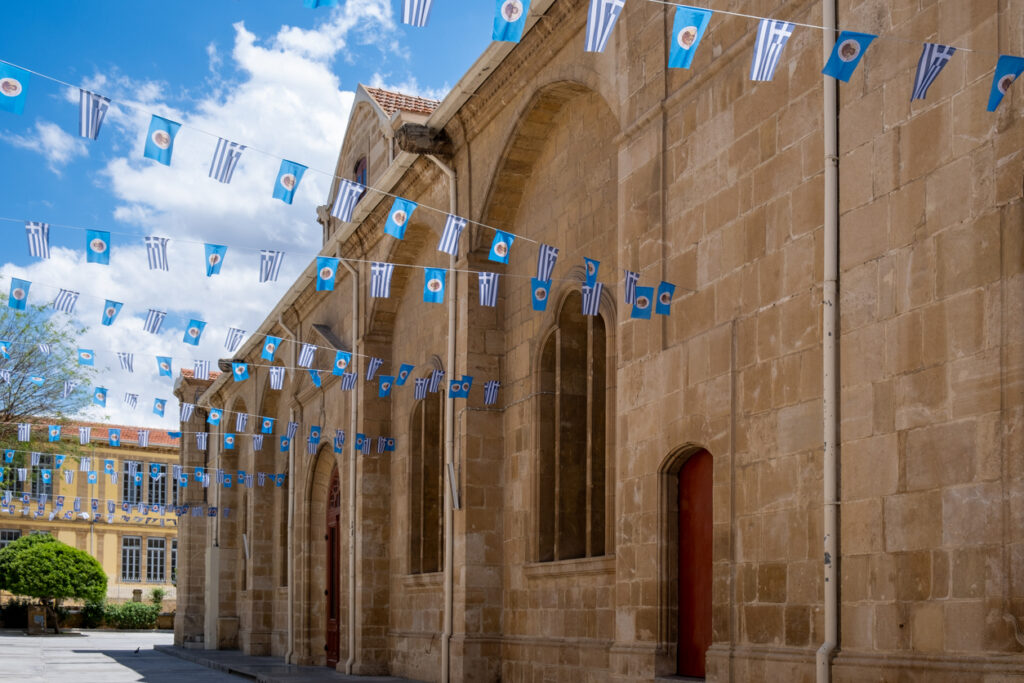Sandfarbene Kirchenmauern in Lefkosia mit blau-weißen Girlanden.