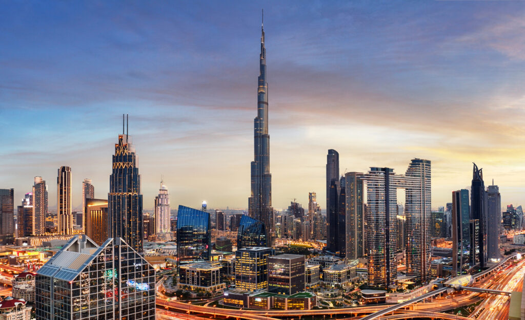 Panorama mit Burj Khalifa und beleuchteten Hochhäusern in der Dämmerung.
