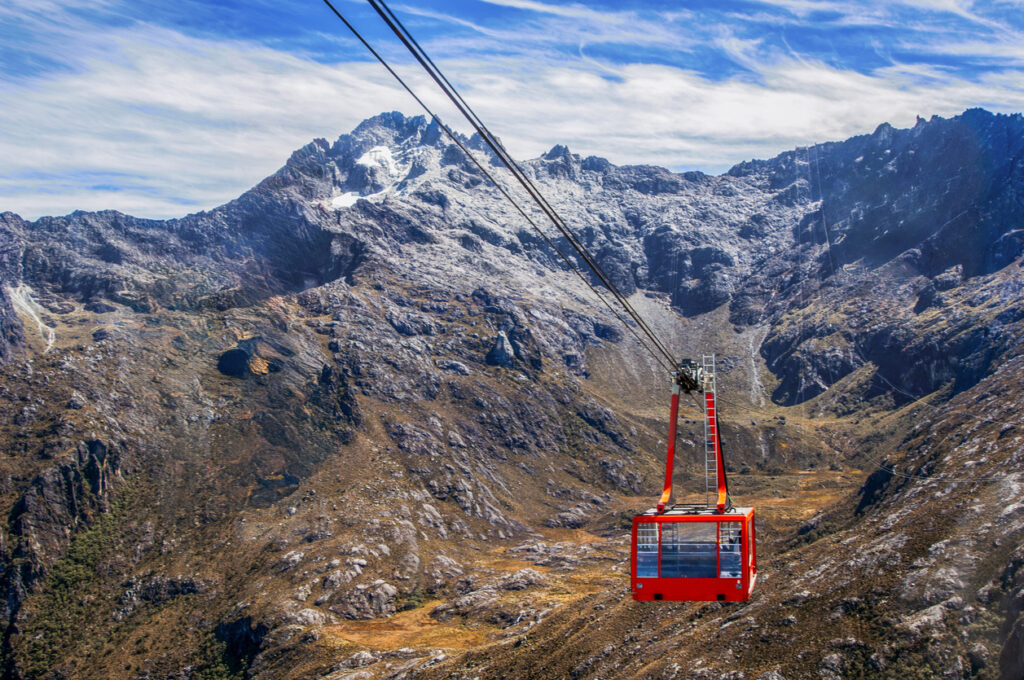 Rote Kabine des Teleférico Mukumbarí schwebt vor schroffen Gipfeln.