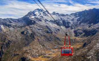 Rote Kabine des Teleférico Mukumbarí schwebt vor schroffen Gipfeln.