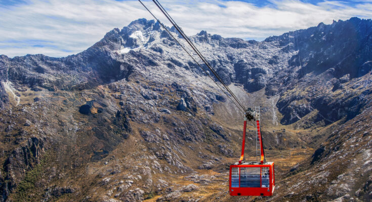 Rote Kabine des Teleférico Mukumbarí schwebt vor schroffen Gipfeln.