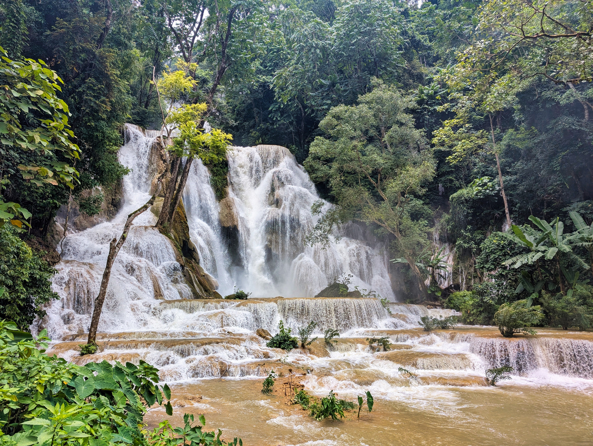 Mehrstufige Kaskaden rauschen durch den dichten Wald in Laos.