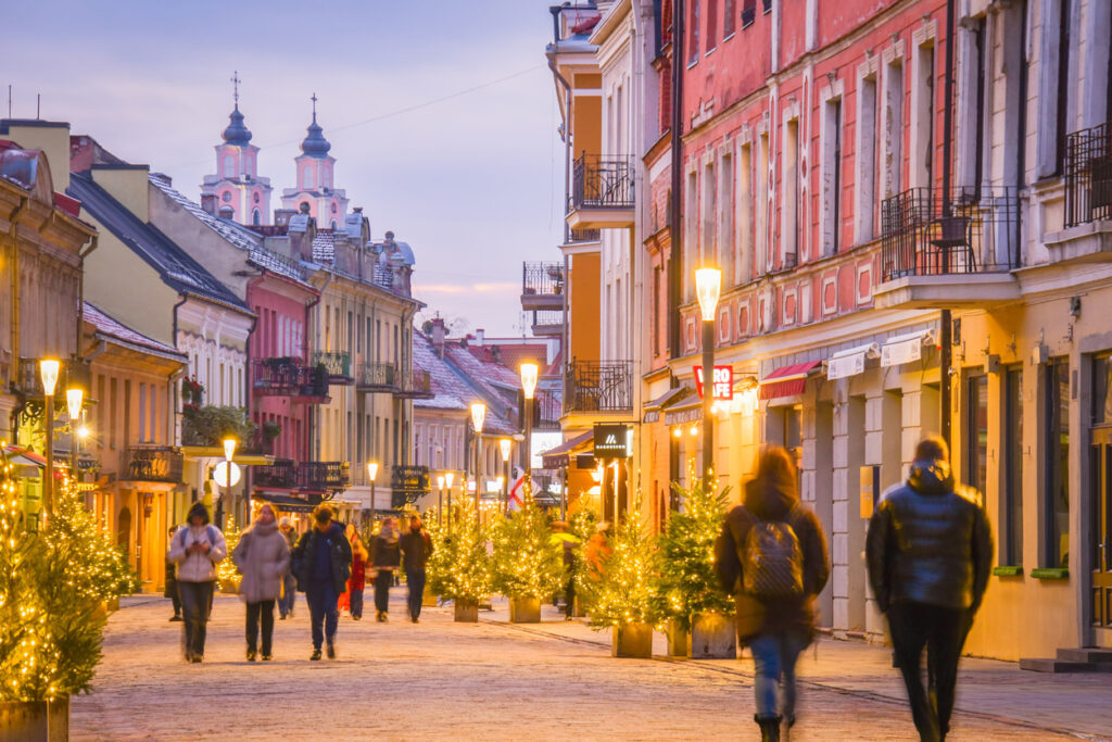 Menschen flanieren zwischen festlich beleuchteten Bäumen auf der Laisvės alėja.
