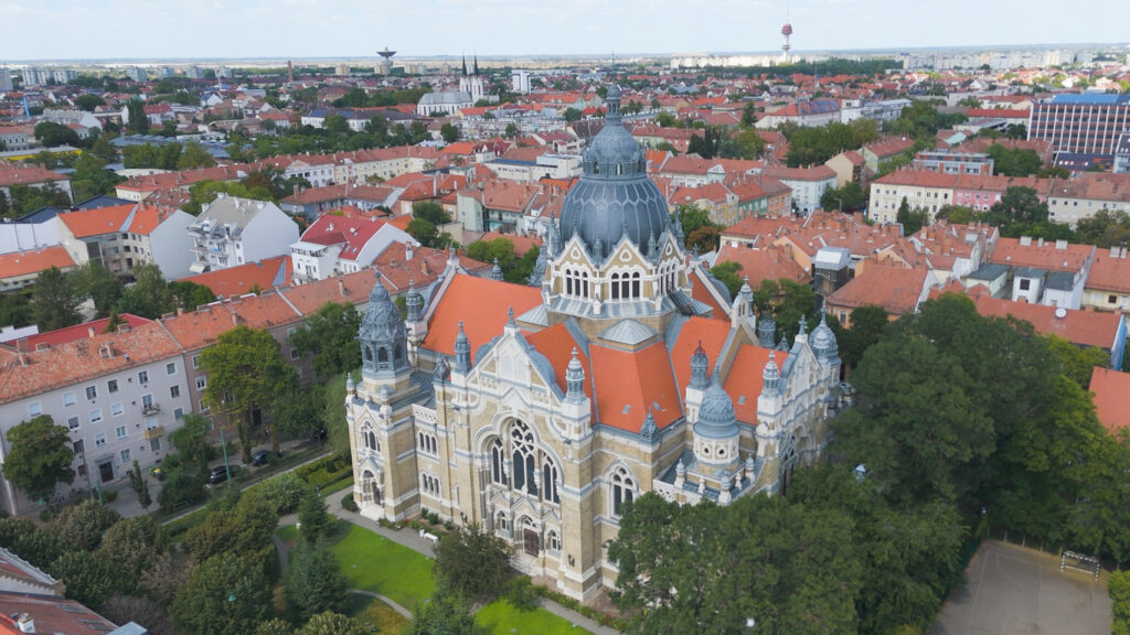 Luftbild der Neuen Synagoge in Szeged mit grauer Kuppel und roten Stadt­dächern.