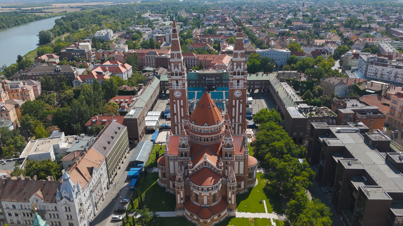 Luftaufnahme der Votivkirche von Szeged mit zwei Türmen und dem nahen Tisza.