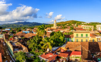 Panorama mit roten Ziegeldächern und gelbem Klosterturm vor dem Escambray-Gebirge.