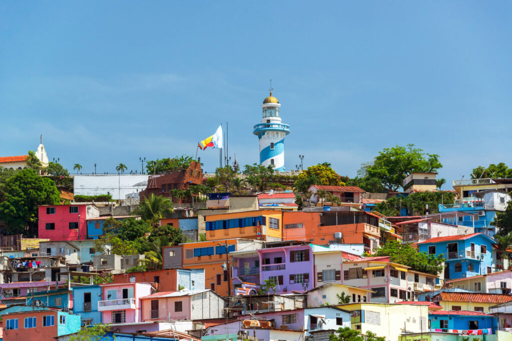 Farbige Häuser an einem Hang mit blau-weißem Leuchtturm in Guayaquil.