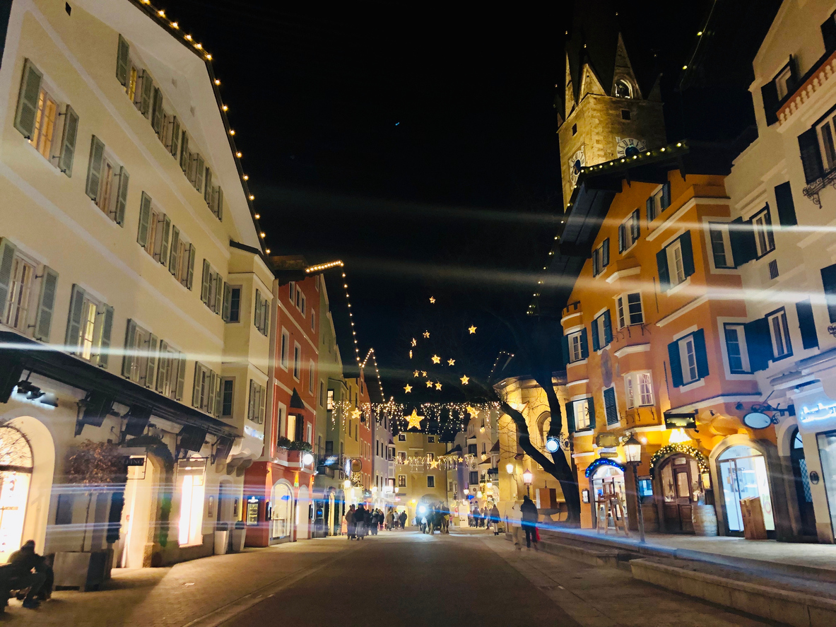 Beleuchtete Häuserfronten und Lichterketten in der Altstadt von Kitzbühel bei Nacht.