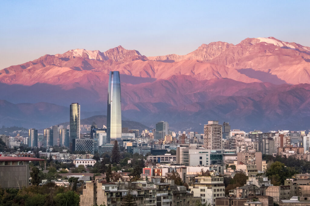 Die Skyline von Santiago, Chile, liegt vor den rötlich leuchtenden Anden mit dem Costanera Center.