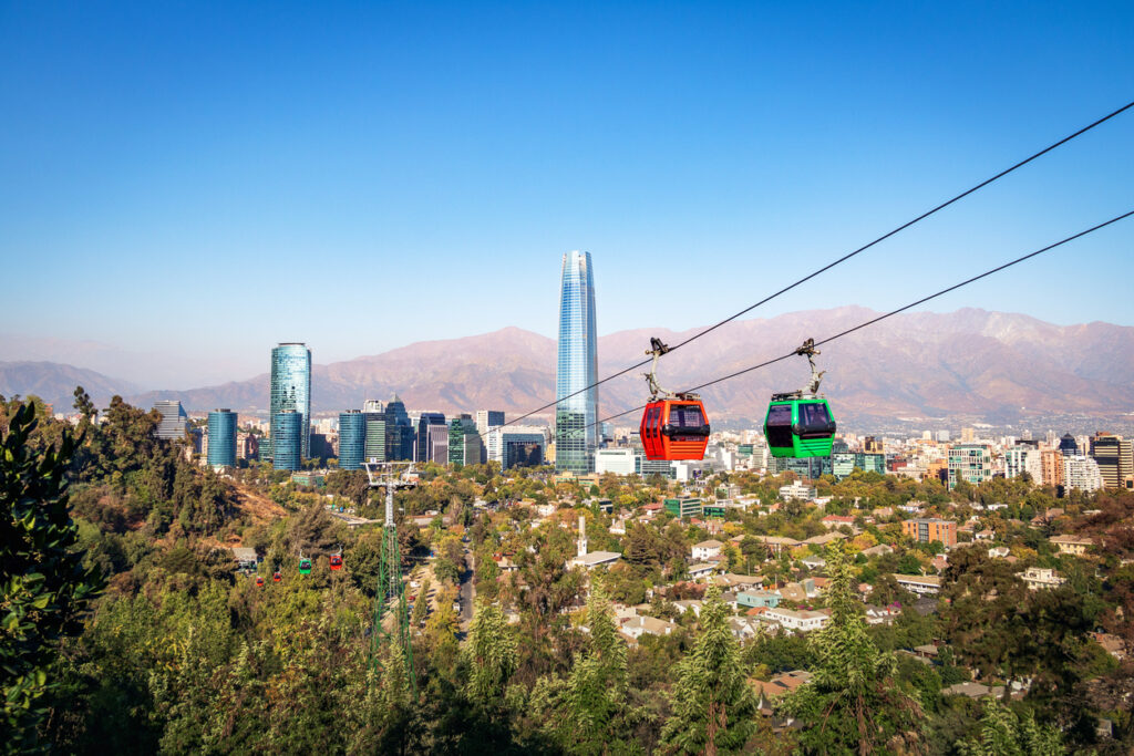 Bunte Seilbahngondeln schweben über Santiago, Chile, mit Blick auf die Skyline und die Anden.