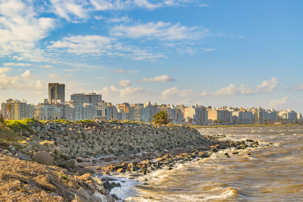 Felsige Uferzone mit Skyline an der Rambla von Montevideo, Uruguay.