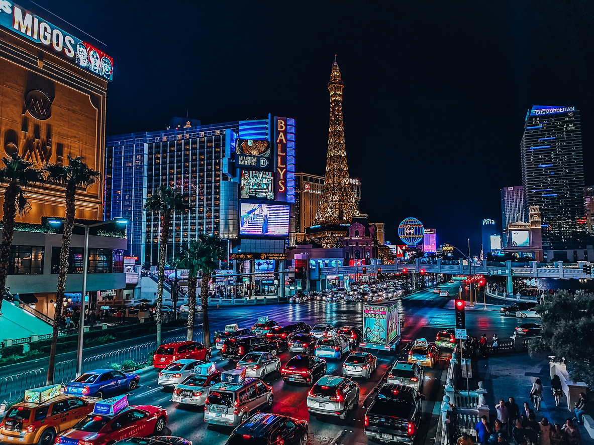 Nächtliche Straßenszene am Las Vegas Strip mit Verkehr, Neonreklamen und dem Eiffelturm von Paris Las Vegas.