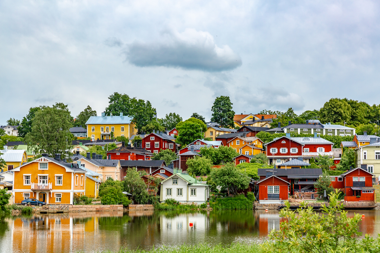 Gelbe, rote und weiße Holzhäuser stehen dicht an einem ruhigen Fluss in Porvoo.