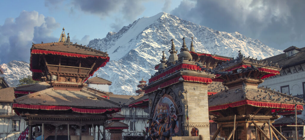 Traditionelle Pagodentempel am Durbar Square in Kathmandu, Nepal, mit schneebedecktem Himalaya im Hintergrund.