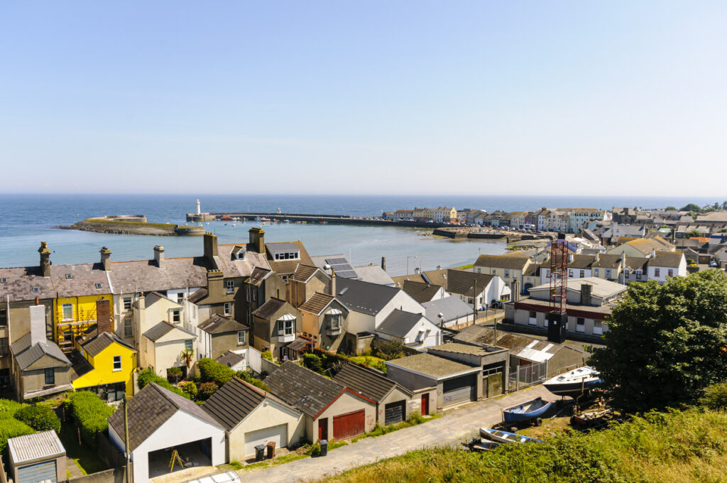 Aussicht auf Donaghadee in Nordirland mit bunten Häusern, Hafenbecken und Leuchtturm am Pier.