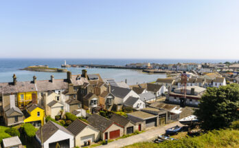 Aussicht auf Donaghadee in Nordirland mit bunten Häusern, Hafenbecken und Leuchtturm am Pier.