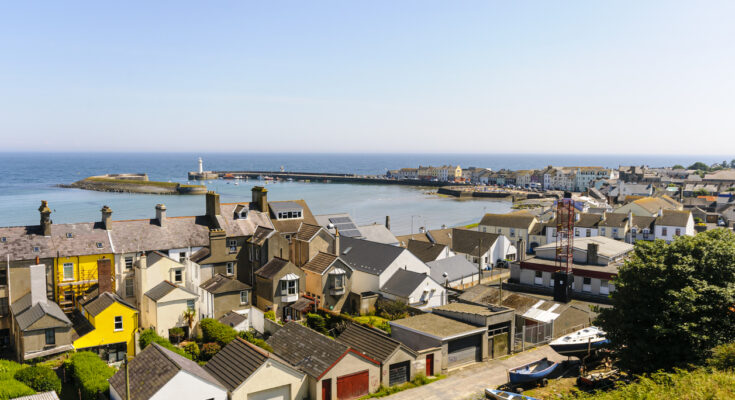 Aussicht auf Donaghadee in Nordirland mit bunten Häusern, Hafenbecken und Leuchtturm am Pier.