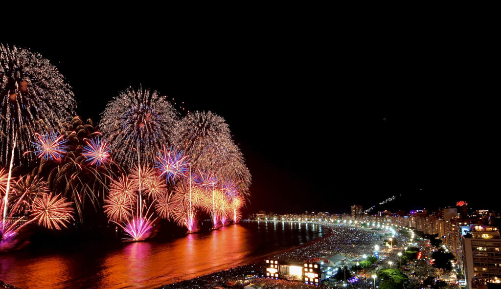 Riesiges Feuerwerk erleuchtet nachts den Strand und die Skyline von Rio de Janeiro.