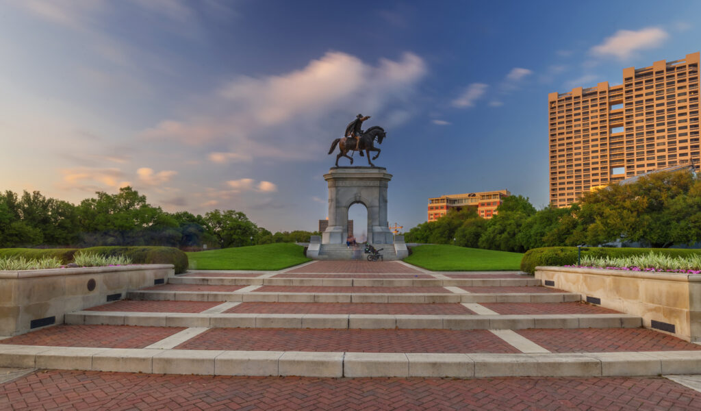 Monumentale Reiterstatue auf einem Torbogen in einem gepflegten Park in Houston mit breiten Treppen im Vordergrund.