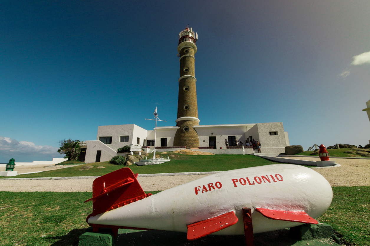 Hoher Leuchtturm mit weißen Gebäuden und der Aufschrift „Faro Polonio“ in Cabo Polonio.