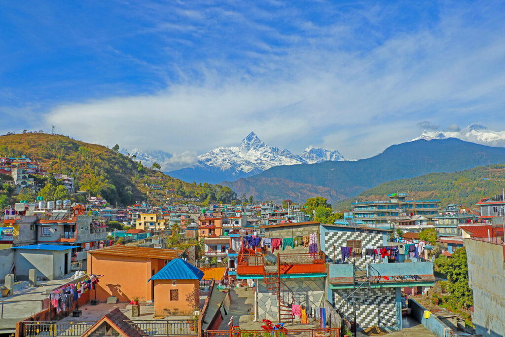 Panorama der Stadt Pokhara mit bunten Häusern und im Hintergrund dem markanten schneebedeckten Machapuchare.