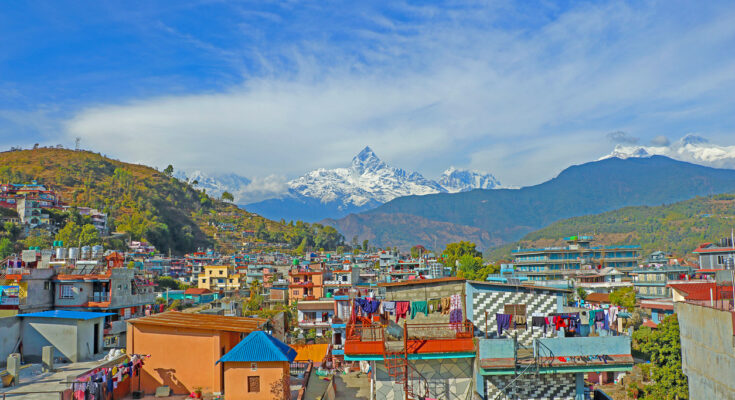 Panorama der Stadt Pokhara mit bunten Häusern und im Hintergrund dem markanten schneebedeckten Machapuchare.
