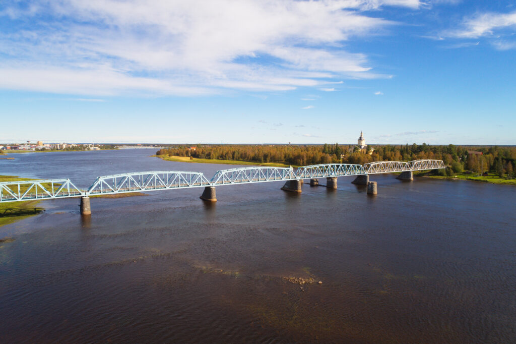 Weite Flussansicht mit heller Eisenbahnbrücke über den Tornio bei Haparanda.